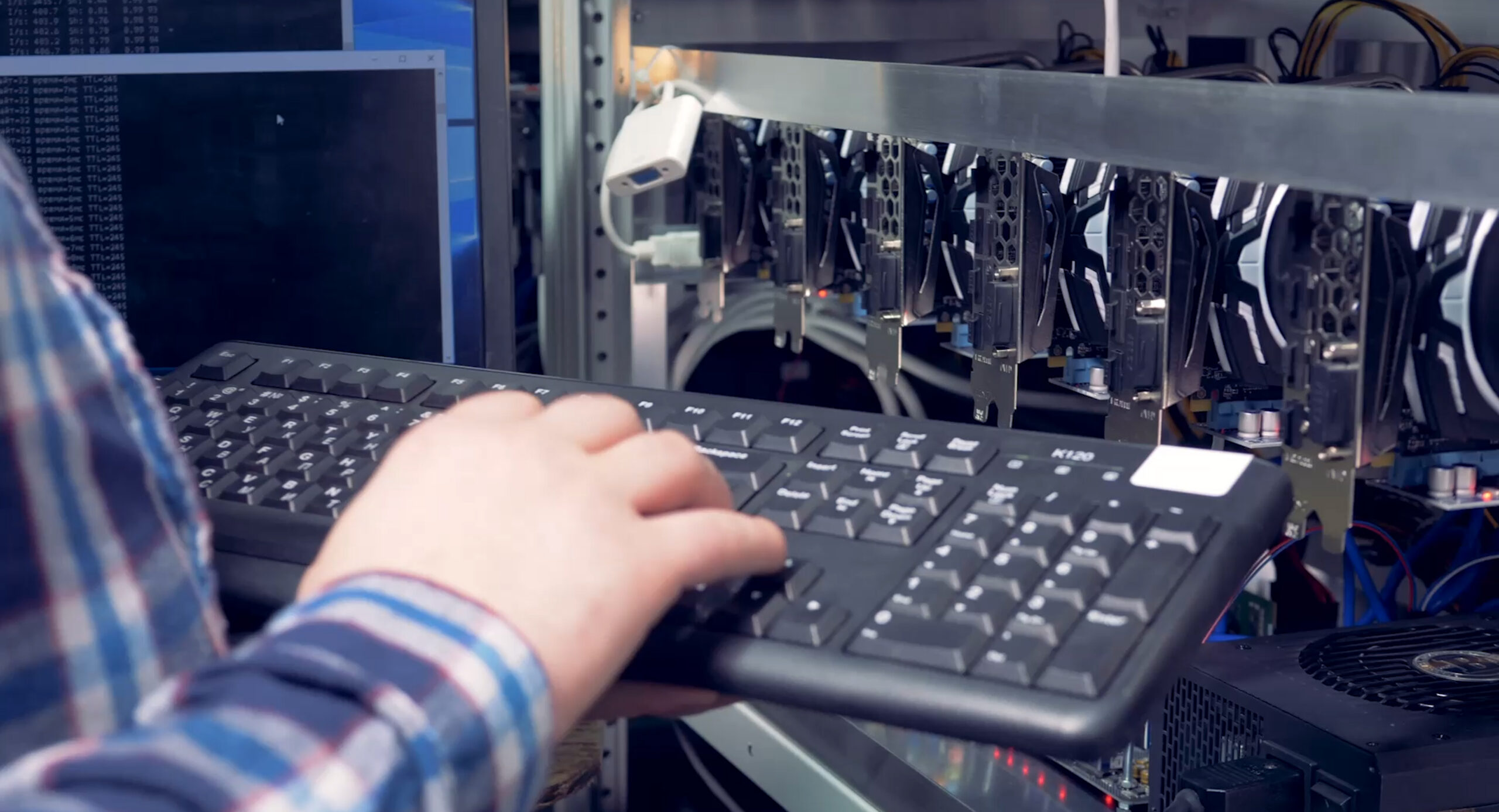 Technicien au clavier devant une baie de cartes graphiques / serveurs